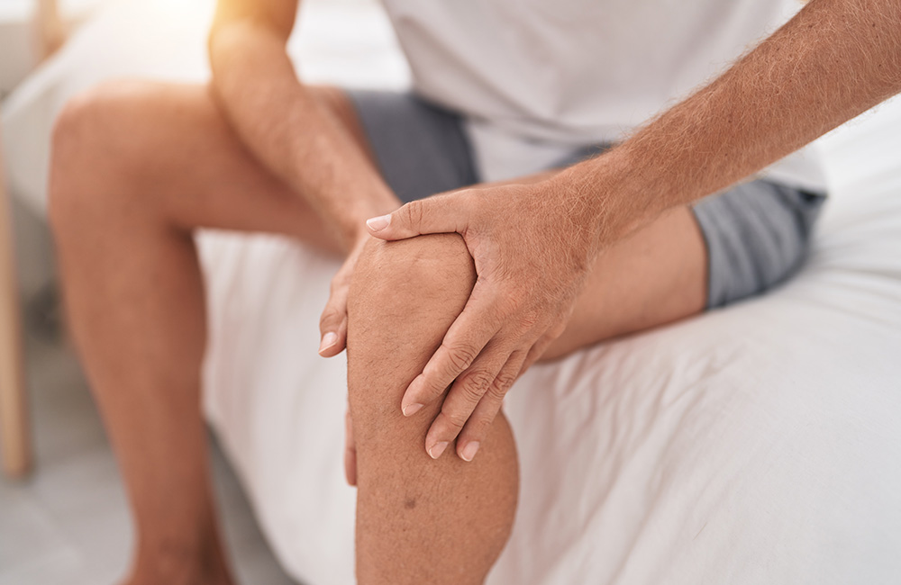 Mann hält sein Knie, symbolisiert Schmerzen durch Arthrose.