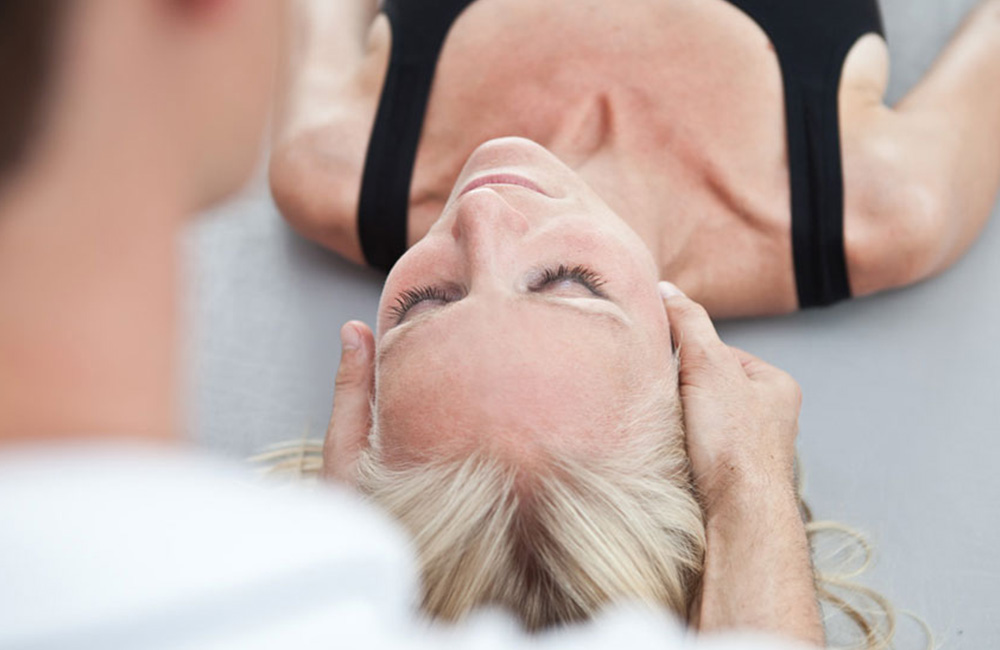 Patientin erhält eine manuelle Therapie am Hals, die Behandlung wird sorgfältig und einfühlsam durchgeführt