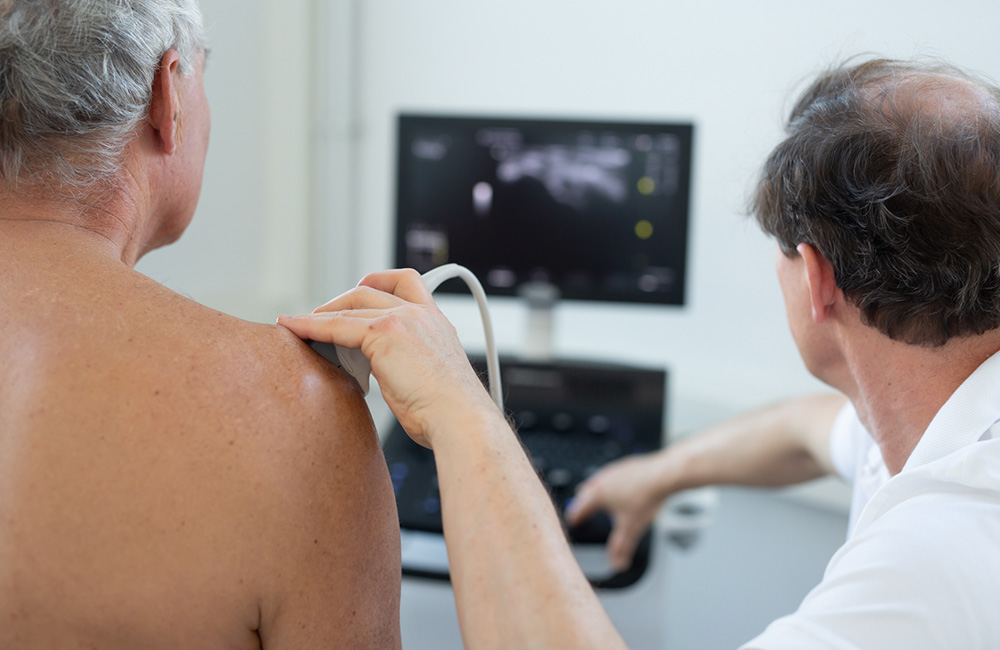 Dr. Nalbach untersucht die Schulter einen Patienten via Ultraschall.