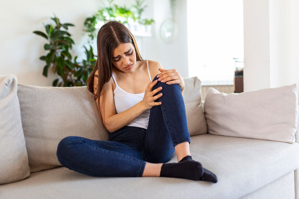 Eine junge Frau fässt sich an ihr Knie und vermutet Sehnenerkrankungen